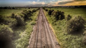 Picture of train tracks running through flat, green fields