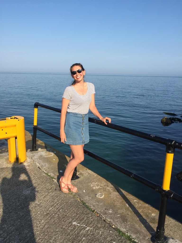 Gaile poses in front of the sea on a sunny day in Ireland