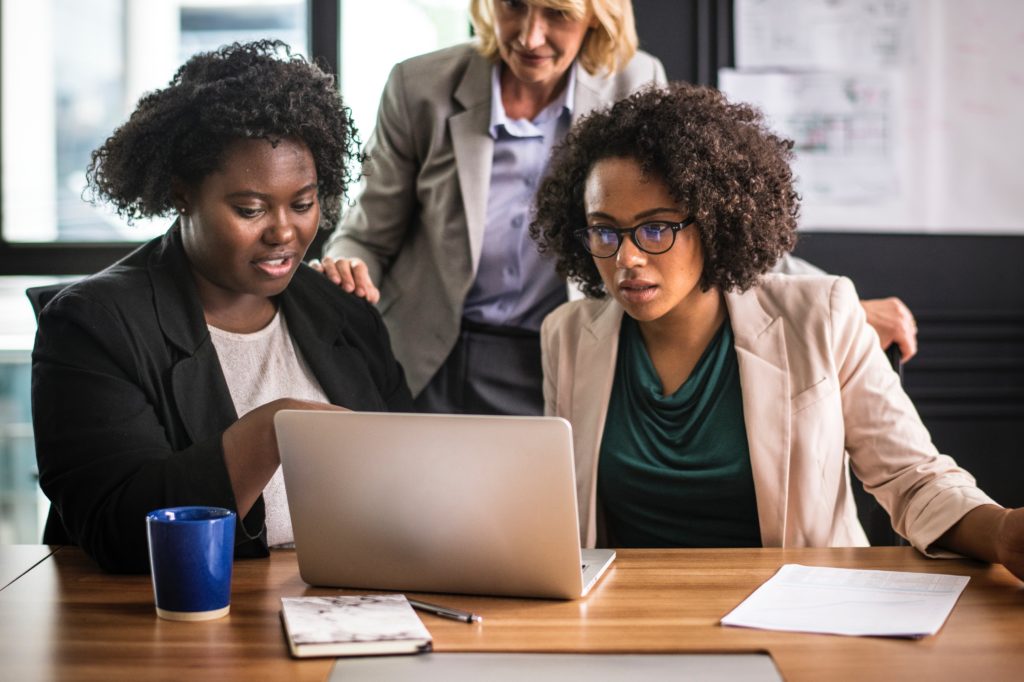 three Interns look at a laptop in an office