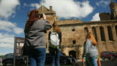 three students stop and observe golden colured castle on a clear day