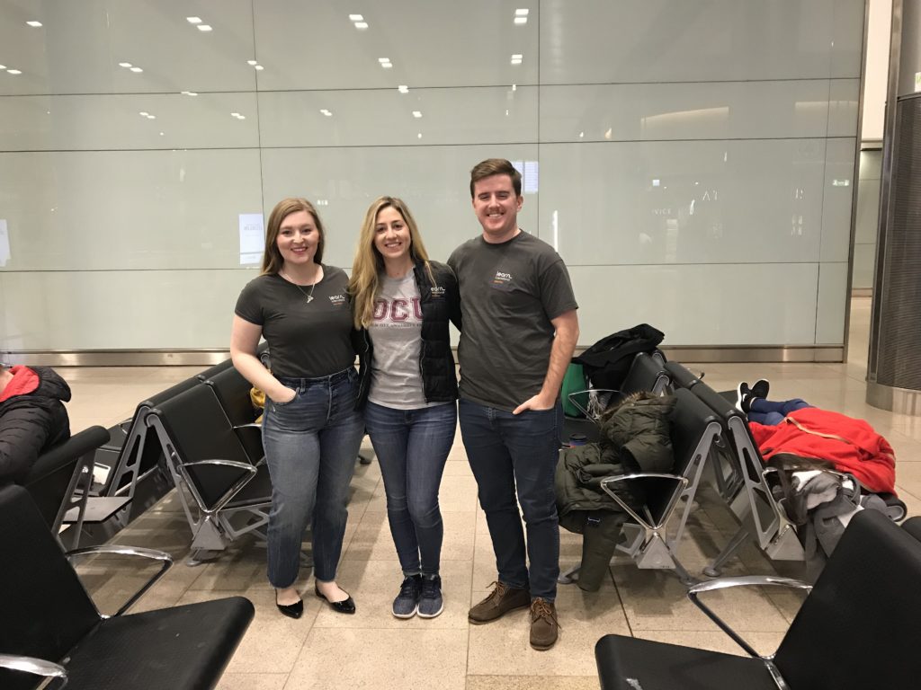 three students stand and pose for a photo in the airport