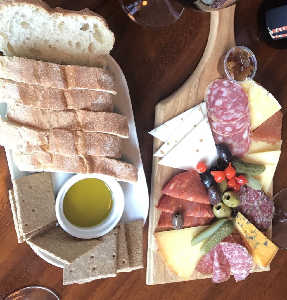 cheese board laid out with selection of meats and bread on a platter