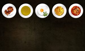 5 plates of various foods laid artistically in a line