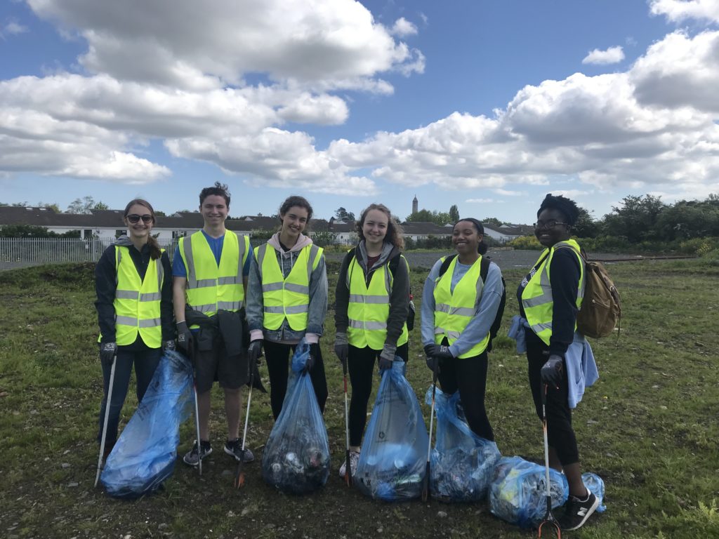 A group of students poses with their trash collecting equipment