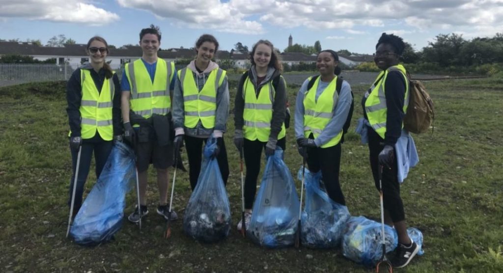 A group of students poses with their trash collecting equipment