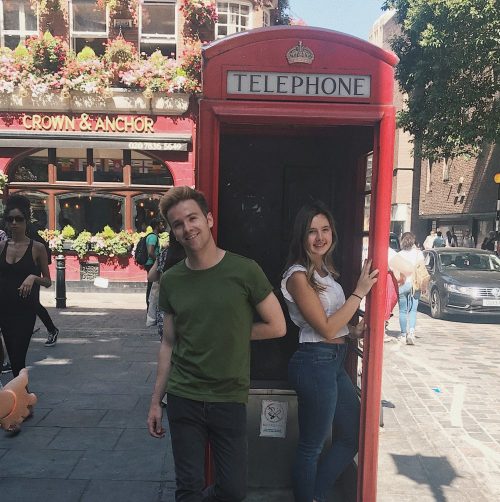London intern posing in a phone booth with partner